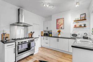 una cucina con armadi bianchi e piano cottura di Stylish 2 bed city centre house a Norwich