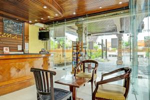 a restaurant with two chairs and a table and a bar at Super OYO Collection O 91081 New Arena Hotel in Kuta