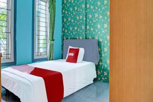Un dormitorio con una cama con una almohada roja. en OYO 91731 Home Stay Elis Cateliya Syariah, en Karawang