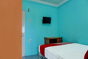 1 dormitorio azul con 1 cama y TV en la pared en OYO 91731 Home Stay Elis Cateliya Syariah, en Karawang