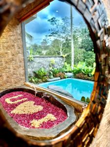 a bathtub filled with pink flowers next to a swimming pool at PONDOK KUNGKANG VILLA 2 in Ubud