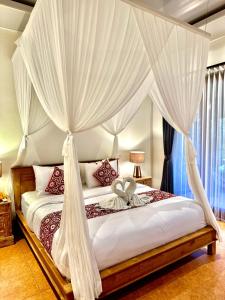 a bedroom with a canopy bed with white drapes at PONDOK KUNGKANG VILLA 2 in Ubud