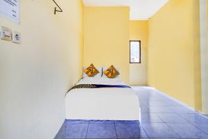 Ce lit se trouve dans un dortoir aux murs jaunes. dans l'établissement OYO Life 90701 Kost Syariah Deris, à Sumedang