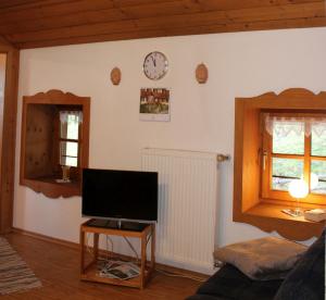 ein Wohnzimmer mit einem TV und einer Uhr an der Wand in der Unterkunft Bernerhof Ferienwohnungen Schmuck in Teisendorf