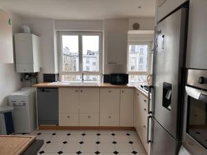 a kitchen with white cabinets and a refrigerator at Jaurès-Pilier rouge/App spacieux/3 chambres/6 pers in Brest