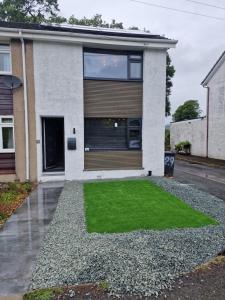 a house with a green lawn in front of it at Bowness - 3 Bed - Hot Tub House in Bowness-on-Windermere