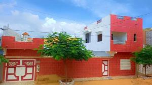 a red and white building with a tree in front at One bedroom appartement with shared pool enclosed garden and wifi at M'bour 2 km away from the beach in Mbour