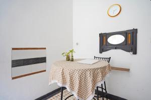 a dining room table with a clock on a wall at OYO 92938 Kost Putih Syariah in Blitar