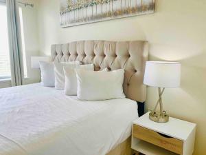 a bed with white pillows and a lamp on a table at Walking Distance from Universal One Bedroom Resort in Orlando