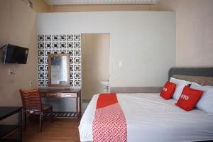 a bedroom with a bed with red pillows and a desk at OYO 93003 B32 Homestay in Medan