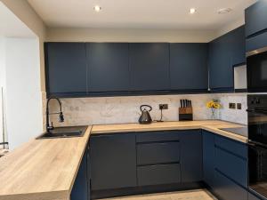 cocina con armarios negros y encimera de madera en Bowness - 3 Bed - Hot Tub House en Bowness-on-Windermere