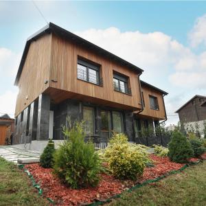 Cette grande maison en bois possède des fenêtres dans une cour. dans l'établissement Moments Villas Premium, Prevalle, à Prizren