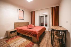 ein Schlafzimmer mit einem Bett mit einer roten Decke und einem Stuhl in der Unterkunft Moments Villas Premium, Prevalle in Prizren