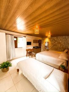 a bedroom with two beds and a stone wall at Pousada do Porto Mar in Pôrto de Pedras