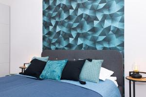 1 dormitorio con cama azul y pared geométrica en Chic207 Retreat: Modern 1BR Gem with Parking by NW, en Budapest