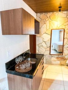 a kitchen with a sink and a mirror with wine glasses at Pousada do Porto Mar in Pôrto de Pedras