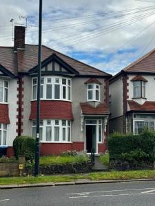 una casa bianca e rossa sul lato di una strada di Smart ROOMS Easy access to Central London By Piccadilly Line a New Southgate