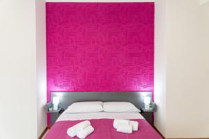 una camera da letto con parete rosa e un letto con asciugamani di May Flower Luxury a Napoli