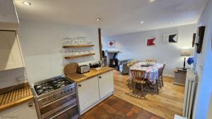 a kitchen and dining room with a table and a stove at Bay Cottage in Portloe