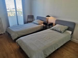 a bedroom with two beds and a lamp on a table at Petit Radet 350m de la plage in Les Sables-dʼOlonne