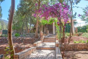 a garden with an arch with purple flowers at Dar Arraha Ouirgane in Ouirgane