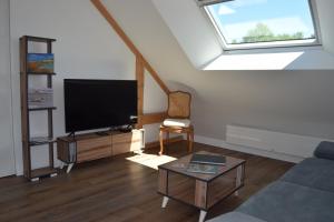 uma sala de estar com uma televisão de ecrã plano e uma janela em Les chambres d hôtes de l entre deux baies à Merlimont entre Berck et le Touquet em Merlimont