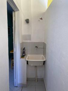 a white bathroom with a sink in a room at Aconchego Mineiro com Garagem in Belo Horizonte