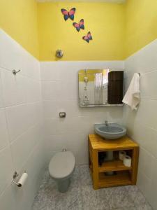 a bathroom with a toilet and a sink with butterflies on the wall at Aconchego Mineiro com Garagem in Belo Horizonte