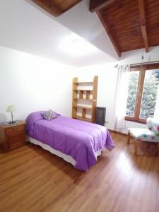 1 dormitorio con 1 cama de color púrpura y 1 silla en Cálido departamento céntrico en San Martín de los Andes en San Martín de los Andes
