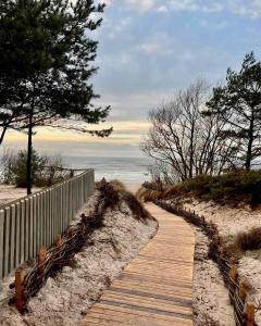 a wooden path to the beach with a fence and trees at SPA apartamentai Palanga in Palanga