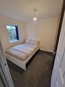 um pequeno quarto com uma cama e uma janela em Comfy 3 bed home em Nottingham