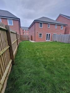 a yard with a fence in front of a brick building at Comfy 3 bed home in Nottingham