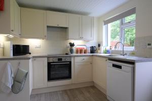 a kitchen with white cabinets and a sink at Ardview Cottage in Oban