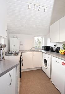 una cucina con armadi bianchi e una lavatrice/asciugatrice di Whifflet Apartment by Klass Living Coatbridge a Coatbridge