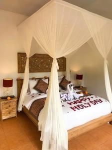 a bedroom with a large white bed with a canopy at PONDOK KUNGKANG VILLA 2 in Ubud