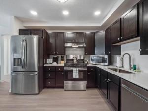 a kitchen with wooden cabinets and a stainless steel refrigerator at NEW Amazing 3 Bedroom Apartment Vista Cay Resort in Orlando