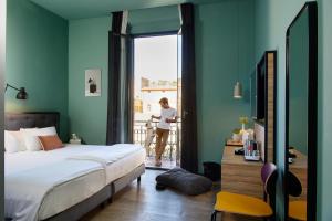 a woman standing on a balcony looking out a bedroom window at The Poet Hotel in La Spezia