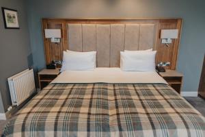Golflinks Hotel في بورتراش: غرفة نوم بسرير كبير وبطانية منقوشة