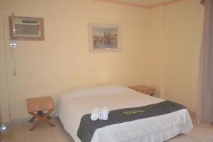 a bedroom with a bed with slippers on it at Hotel Canto do Atlântico in Guarujá