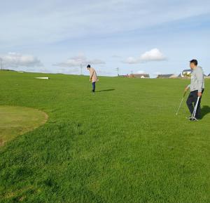 two men are playing frisbee in a field at The Boathouse in Cork