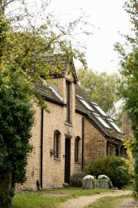 un antiguo edificio de ladrillo con ventanas y una puerta en Colthorn Farm Cottage By Aryas Properties - Oxford, en Oxford