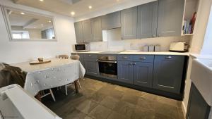 a kitchen with blue cabinets and a table with a table cloth at Beach Hill Cottage in Portloe