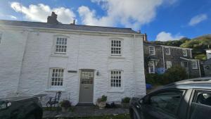 une maison blanche avec une voiture garée devant elle dans l'établissement Beach Hill Cottage, à Portloe