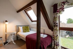 a attic bedroom with a bed and a window at Colthorn Farm Cottage By Aryas Properties - Oxford in Oxford