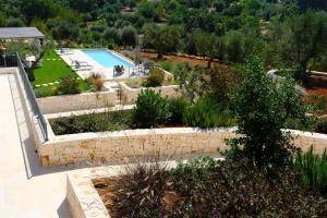 uma vista exterior para um jardim com uma piscina em Trullo Mamamè em Cisternino