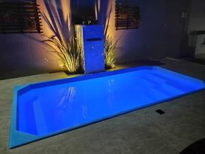 ein blauer Pool in einem Haus mit Lichtern in der Unterkunft Casa de praia em Setiba in Guarapari