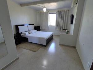 1 dormitorio con cama blanca y ventana en Casa de praia em Setiba, en Guarapari