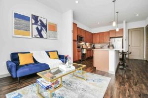 a living room with a blue couch and a kitchen at HTown Downtown Oasis in Houston