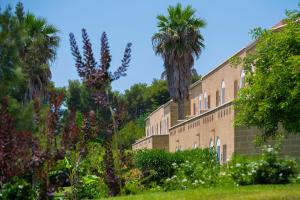 un grande edificio in mattoni con palme sullo sfondo di Vivosa Apulia Resort a Ugento