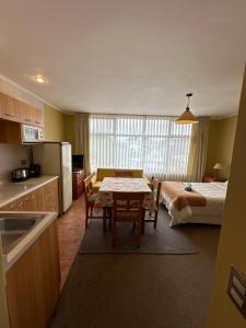 Una cocina con una mesa y una habitación con una cama. en Apart hotel Terra Valdivia, en Valdivia